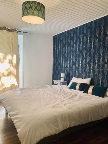 une chambre avec un grand lit blanc avec une tête de lit bleue dans l'établissement Maison 2 chambres- grand jardin-WIFI - au cœur du village AUBETERRE -visites- conciergerie J&N, à Aubeterre-sur-Dronne