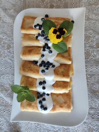 a plate of pancakes with blueberries and a flower on it at Leśny Dworek in Kryłatka