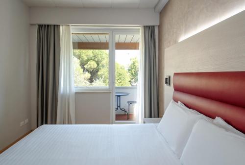 a bedroom with a bed with a red headboard and a window at Hotel Palace del Conero in Osimo
