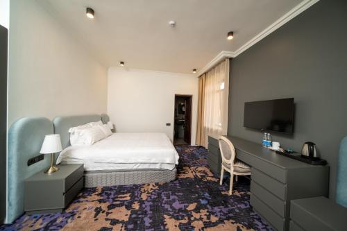 a hotel room with a bed and a flat screen tv at Kefilyan Family Hotel in Haghpat
