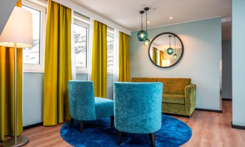 a living room with blue chairs and a mirror at Thon Hotel Hammerfest in Hammerfest