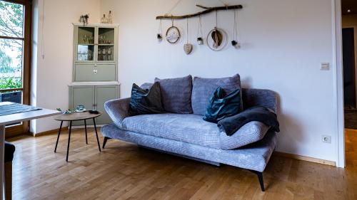 a living room with a blue couch and a table at FeWo Vergissmeinnicht in Scheidegg