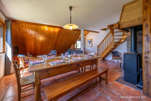 a dining room with a wooden table and a stove at Chalet la Forestière in Orcières