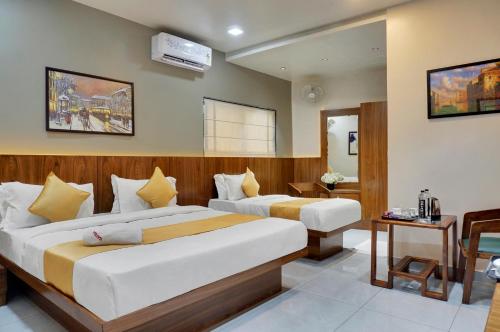 a hotel room with two beds and a television at Hotel Sayba Executive in Pune