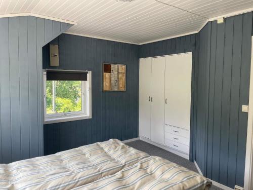 a bedroom with blue walls and a bed and a window at 6 person holiday home in BØMLO in Bømlo