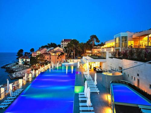 a swimming pool with chairs and the ocean at night at Apartment in Veli Losinj by the Sea in Veli Lošinj