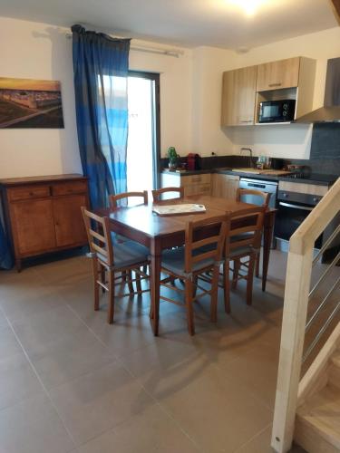 - une cuisine avec une table à manger en bois et des chaises dans l'établissement Maison vacances, à Aigues-Mortes