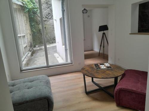 a living room with a table and a couch and a window at Appartement 75m2 plein centre face a la mairie in Morlaix