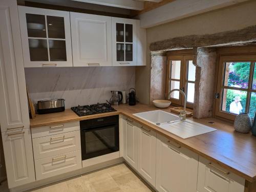 une cuisine avec des armoires blanches et un évier dans l'établissement La Saugeraie - Renovated cottage for 2 in historic village, à Burnand