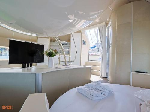 une chambre blanche avec une télévision et un lit avec dans l'établissement ANTHENEA Suite Hôtelière Flottante, à Perros-Guirec