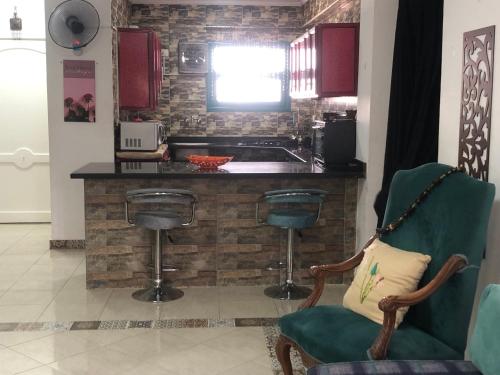 a kitchen with a green chair and a counter at Paradise Gates Golden Beach two in Ras Sedr