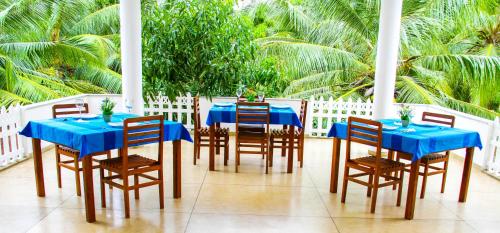 a dining room with blue tables and chairs and palm trees at Hotel Nilketha Yala Tissamaharama in Tissamaharama