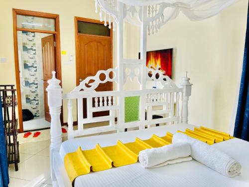 a white bed with yellow pillows in a room at Elna's Nyali - Work & Unwind - Pool, Sea Views, AC & Fast Wi-Fi in Mombasa