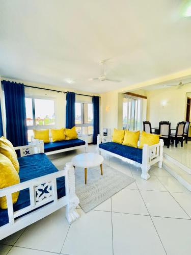 a living room with two beds and yellow pillows at Elna's Nyali - Work & Unwind - Pool, Sea Views, AC & Fast Wi-Fi in Mombasa