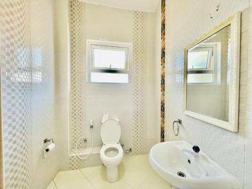 a bathroom with a toilet and a sink and a mirror at Elna's Nyali - Work & Unwind - Pool, Sea Views, AC & Fast Wi-Fi in Mombasa