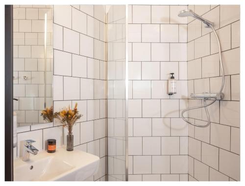 a white tiled bathroom with a sink and a shower at Eklo Montpellier Centre Gare in Montpellier