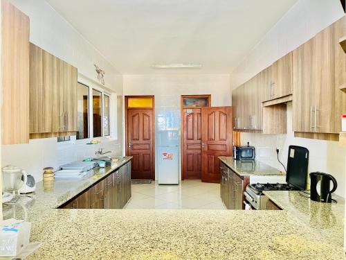 a large kitchen with wooden cabinets and a refrigerator at Elna's Nyali - Work & Unwind - Pool, Sea Views, AC & Fast Wi-Fi in Mombasa