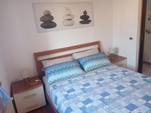 a bedroom with a bed with a blue and white comforter at Appartamento 'Io e te' in Pieve dʼAlpago