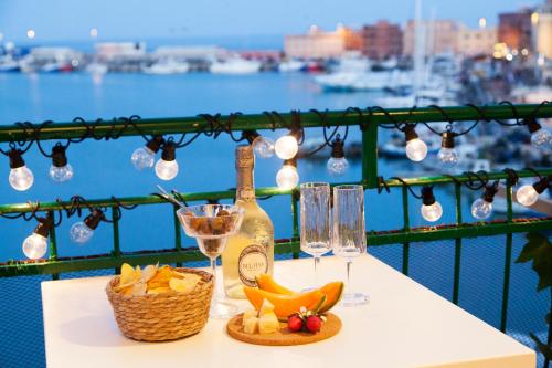 un tavolo con una bottiglia di vino e un cesto di frutta di La Finestra Sul Mare Central Apartment Vista mare ad Anzio