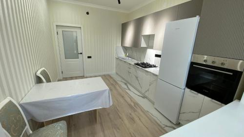 a kitchen with a white table and a white refrigerator at Уютная 1-ком кв в Жк Альтаир мкр Батыс-2 in Aktobe
