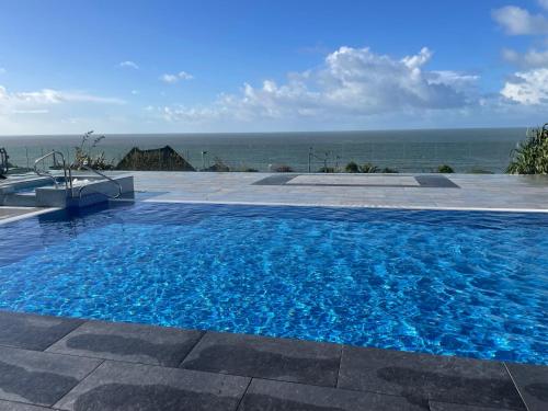 a large blue swimming pool with the ocean in the background at Swyn y Mor beach close Pet friendly hot tub in Barmouth