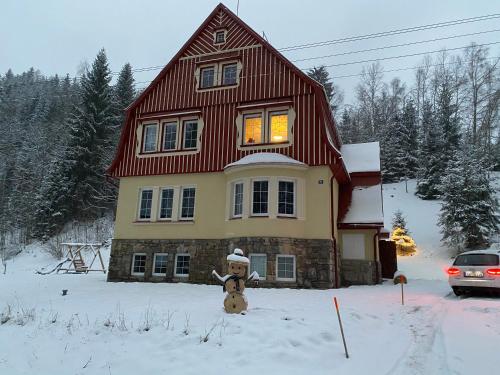 a teddy bear standing in the snow in front of a house at vilavítkovice in Vítkovice