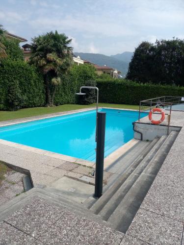 a blue swimming pool with stairs next to a house at APPARTAMENTO GHITA in Baveno