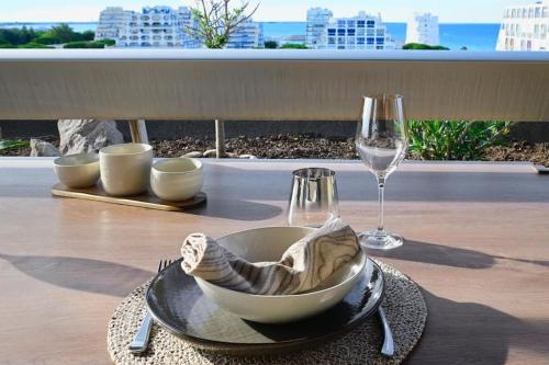 a table with a bowl and a glass of wine at Sublime Appart Vue mer Piscine Clim in La Grande-Motte