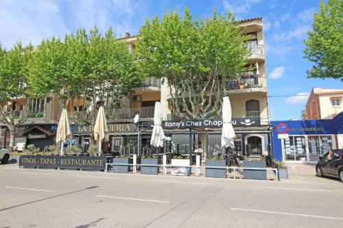 a street in front of a building with umbrellas at Basic Comfort Studio Poblat tipic 0168 in Empuriabrava