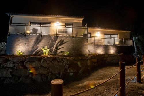 a house at night with a stone wall and lights at Casa Léa in Sollacaro
