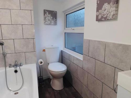 a bathroom with a toilet and a tub and a window at Well appointed terraced property in Kent