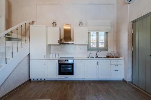 a kitchen with white cabinets and a sink and a staircase at Chroma Pelion Villas in Kato Gatzea