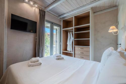 a bedroom with a white bed with a tv on the wall at Chroma Pelion Villas in Kato Gatzea