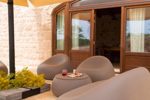 a patio with chairs and a table with a glass of wine at DONNAPAOLA MODERN FARM in Altamura