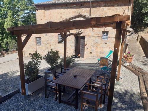 a wooden table and chairs under a wooden pergola at Tenuta della Selva in Murlo