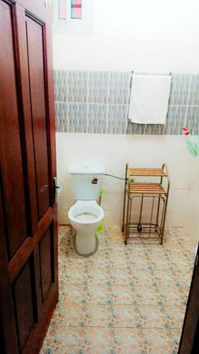 a bathroom with a toilet and a chair in it at Résidence NKOA in Yaoundé
