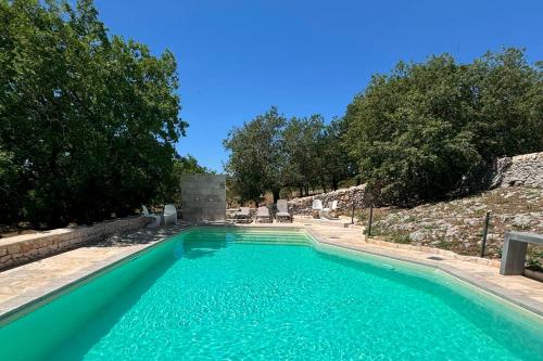 a swimming pool with turquoise water and trees at DONNAPAOLA MODERN FARM in Altamura