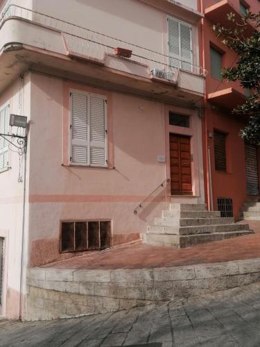 a pink building with stairs and a door at Sa Sartoria in Bolotana