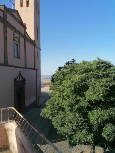 a tree in front of a building with a staircase at Sa Sartoria in Bolotana