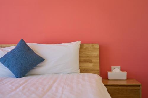 a bedroom with a bed with a red wall at OwlStay Green Villa in Pinghe