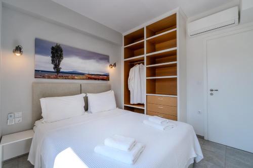 a bedroom with a white bed with towels on it at Chroma Pelion Villas in Kato Gatzea