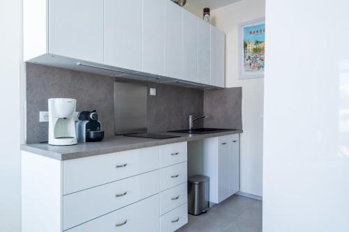 une cuisine avec des armoires blanches et un évier dans l'établissement Studio de la Villa - Welkeys, à Bandol
