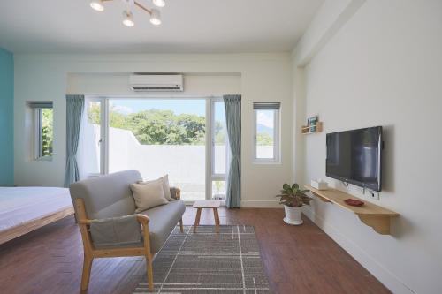 a bedroom with a bed and a tv and a chair at OwlStay Green Villa in Pinghe
