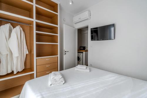 a white bedroom with a bed and a tv at Chroma Pelion Villas in Kato Gatzea