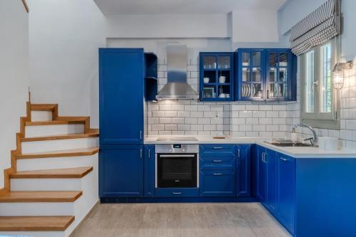 a blue kitchen with blue cabinets and a staircase at Chroma Pelion Villas in Kato Gatzea