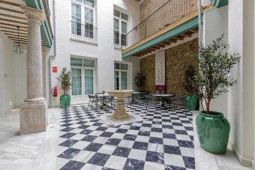 a courtyard with tables and chairs on a checkered floor at Palacio Vegafuente by Caleta Homes in Málaga