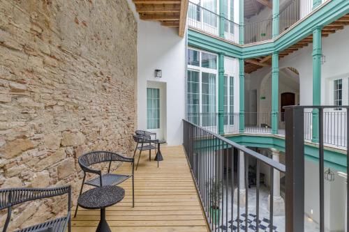 a balcony with two chairs and a stone wall at Palacio Vegafuente by Caleta Homes in Málaga