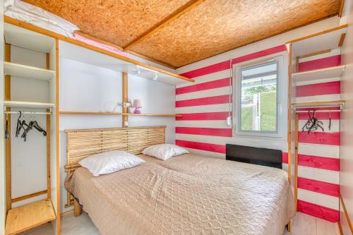 a small bedroom with a bed and a window at Chalet B Village Vacances in Gujan-Mestras