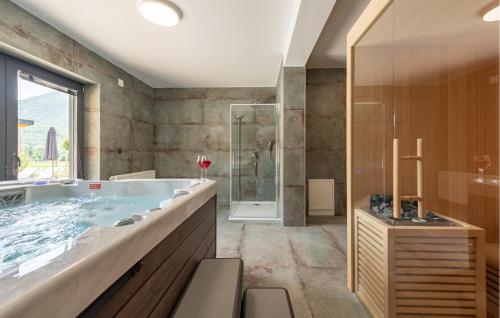a bathroom with a tub and a glass shower at Stunning Home In Rizvanusa With Sauna in Rizvanuša