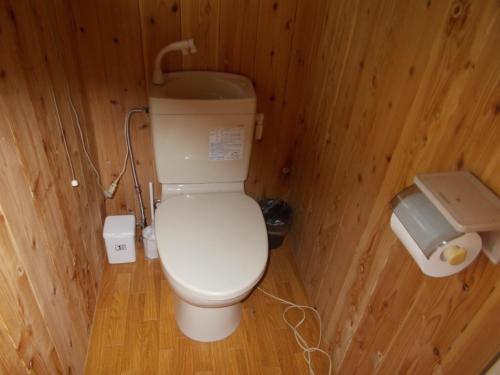a small bathroom with a toilet in a wooden wall at SDGs house with shower room - Vacation STAY 34864v in Yufu